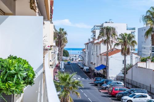 une rue de la ville avec des voitures garées et des palmiers dans l'établissement 2 bedrooms with terrace 100 metres from the sea, à Cannes