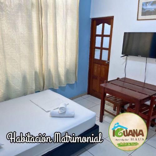 a room with a bed and a chair and a television at IGUANA HAUS IQUITOS in Iquitos