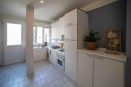 Il comprend une cuisine avec des placards blancs et du carrelage blanc. dans l'établissement ginalia cottage, à Éclaron