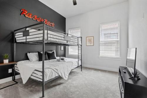 ein Schlafzimmer mit einem Metalletagenbett und einem TV in der Unterkunft Hog Heaven- 1 2 Mile to DT Fayetteville-Sleeps 8 in Fayetteville