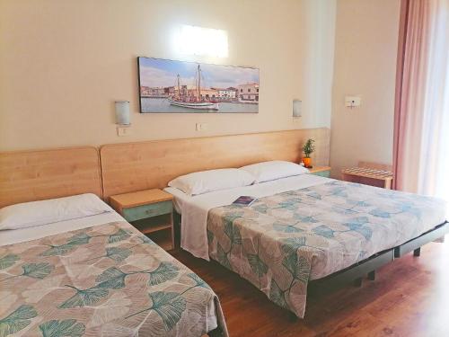 ein Hotelzimmer mit 2 Betten und einem Bild an der Wand in der Unterkunft California Pastry Hotel in Cervia
