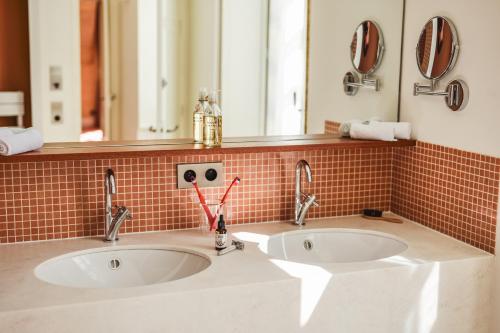 two sinks in a bathroom with two mirrors at Domaine de Coeurmandie - Hôtel Château in Bény-sur-Mer