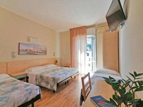 ein Hotelzimmer mit 2 Betten und einem TV in der Unterkunft California Pastry Hotel in Cervia