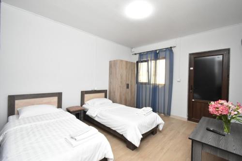 two beds in a room with white walls and wood floors at SIRIK in Armavir