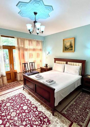 a bedroom with a large bed and a chandelier at Villa Parku Rinia in Korçë