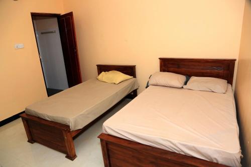 2 letti posti uno accanto all'altro in una camera da letto di Urumpirai Holidays a Jaffna