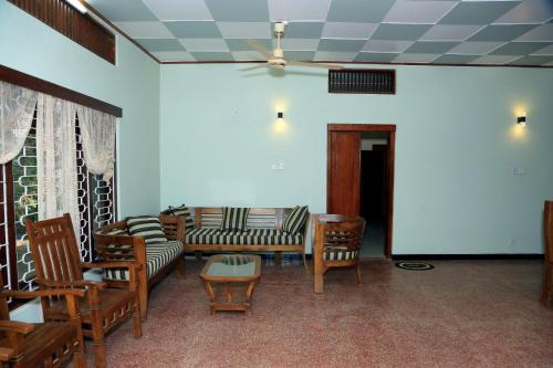 a living room with couches and chairs and a ceiling at Urumpirai Holidays in Jaffna