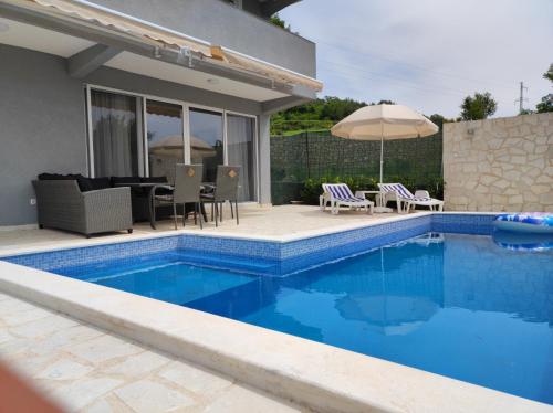 a pool with chairs and an umbrella next to a house at Zelena Maslina in Bar