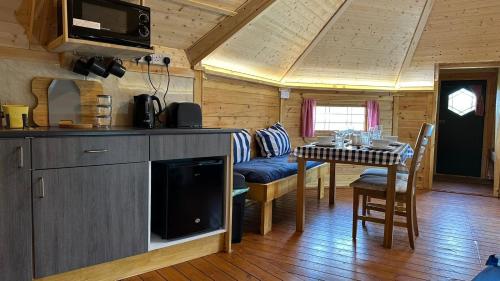 a kitchen and dining room in a log cabin at Holly Tree Glamping Cabins in Wigglesworth
