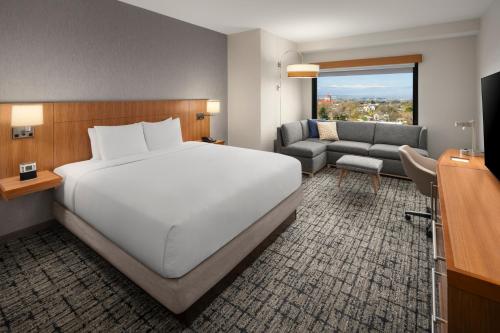 ein Schlafzimmer mit einem großen weißen Bett und einem Sofa in der Unterkunft Hyatt Place Denver Cherry Creek in Denver