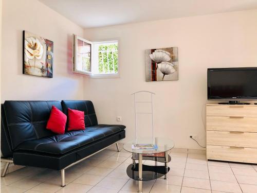 een woonkamer met een zwarte leren bank en een flatscreen-tv bij Emporium Néris - Premium Serviced Apartments in Néris-les-Bains