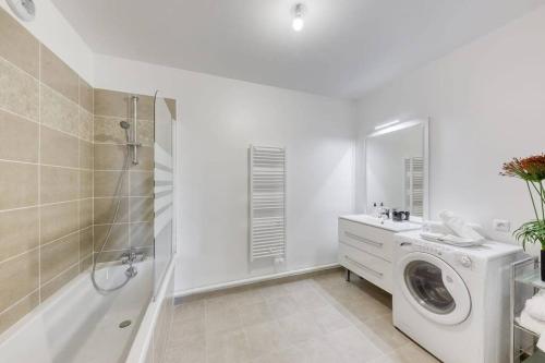 uma casa de banho branca com uma máquina de lavar roupa e um chuveiro em Appartement Neuf avec Terrasse em Bobigny