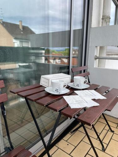 une table avec deux tasses et un micro-ondes sur un balcon dans l'établissement Schirmeck Apartment, à Strasbourg