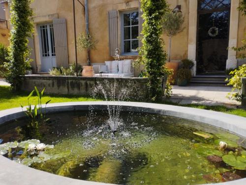 a pond in front of a house with a fountain at Les Tilleuls in Cavaillon