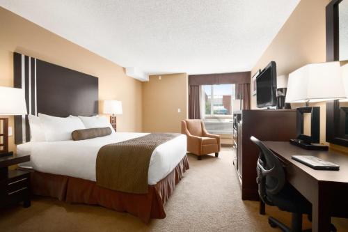 a hotel room with a bed and a desk at Days Inn by Wyndham Calgary Northwest in Calgary