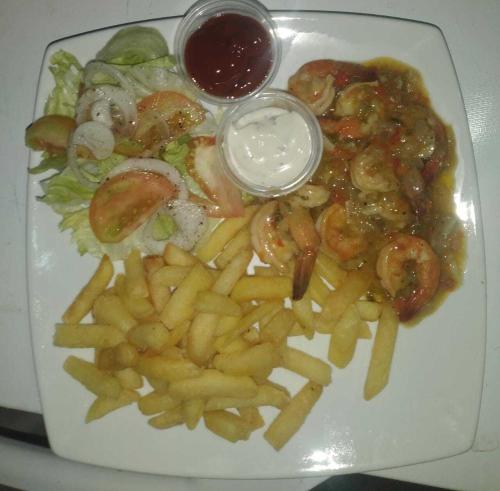 un piatto di cibo con gamberetti, patatine fritte e salsa di Villa Las Mellizas a Puerto Armuelles