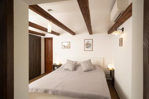 um quarto com uma cama branca e tectos em madeira em Tiny house Laurel em Kostrena