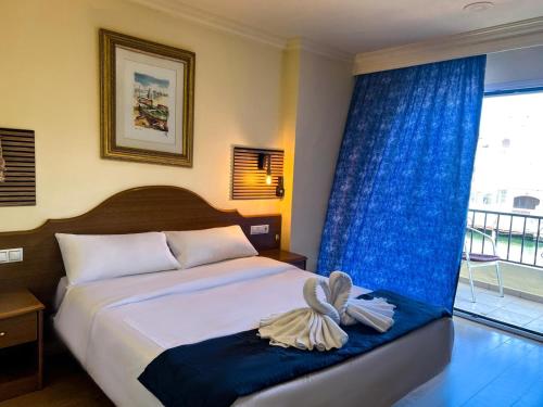 a bedroom with a bed with blue curtains and a window at Hotel Portofino by InsideHome in Empuriabrava