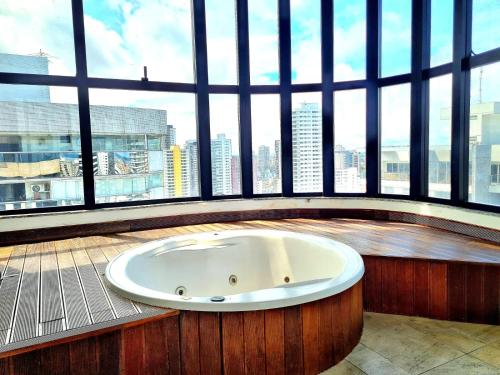 a bath tub in a room with a large window at Royal Duplex Umarizal in Belém