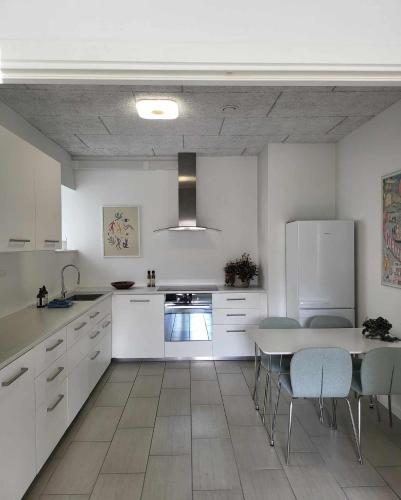 a kitchen with white cabinets and a table and chairs at Charmerende villalejlighed på 80 kvm inklusiv gårdhave in Viby