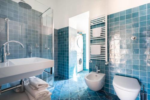baño de azulejos azules con lavabo y aseo en Trevi Comfortable Apartment with Terrace | Romeloft, en Roma