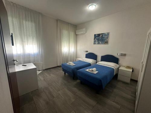 リオーロ・テルメにあるHotel Francaのベッドルーム1室(青いベッド2台、テーブル付)