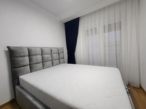 een wit bed in een kamer met een raam bij Eleven Apartment in Podgorica