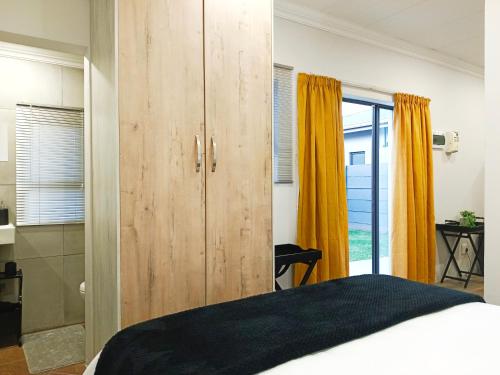 ein Schlafzimmer mit einem großen Holzschrank und einem Bett in der Unterkunft Olive Tree Studio Apartment in Harrismith