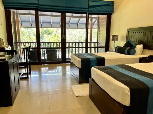 a hotel room with two beds and a balcony at Hotel Randiya Anuradhapura in Anuradhapura