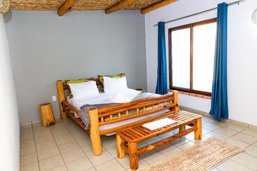 um quarto com uma cama de madeira e uma janela em Telvina Beach Lodge em Vilanculos