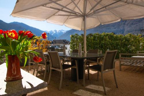 a table and chairs with an umbrella and flowers at LE 41 AVENUE FOCH in Luchon