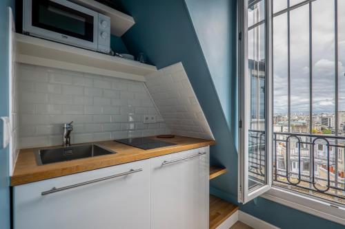 une cuisine avec un évier et une fenêtre dans l'établissement GoodGuest-Trocadéro Tour Eiffel Bail Mobilité, à Paris