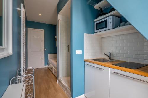 une cuisine avec des murs bleus et des armoires blanches dans l'établissement GoodGuest-Trocadéro Tour Eiffel Bail Mobilité, à Paris