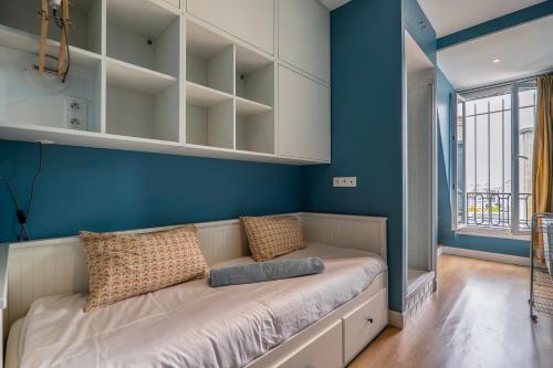 - un canapé dans une chambre dotée d'un mur bleu dans l'établissement GoodGuest-Trocadéro Tour Eiffel Bail Mobilité, à Paris