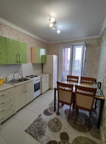 una cocina con mesa y sillas y una cocina con armarios verdes en Квартира 3-х комнатная, en Madaliabad