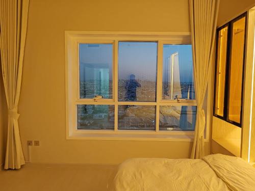 a bedroom with a window with a view of the city at Corniche Tower in Ajman 