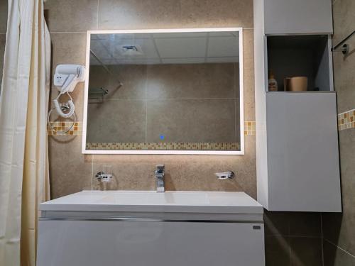 a bathroom with a white sink and a mirror at Corniche Tower in Ajman 