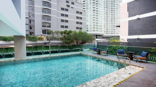 a swimming pool with chairs and a table and buildings at Holiday Inn Express & Suites Bangkok Central Pier by IHG in Bangkok