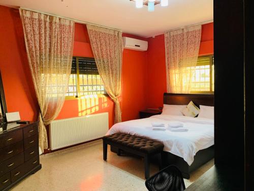 Schlafzimmer mit orangefarbenen Wänden, einem Bett und einem Fenster in der Unterkunft Laura's Stylish Villa in Madaba