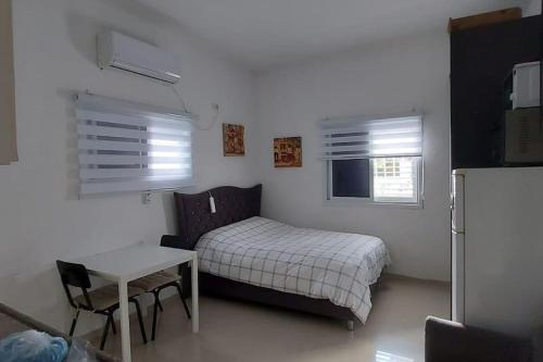 1 dormitorio con 1 cama, mesa y nevera en Luxury Huge Suite Near the beach, en Bat Yam