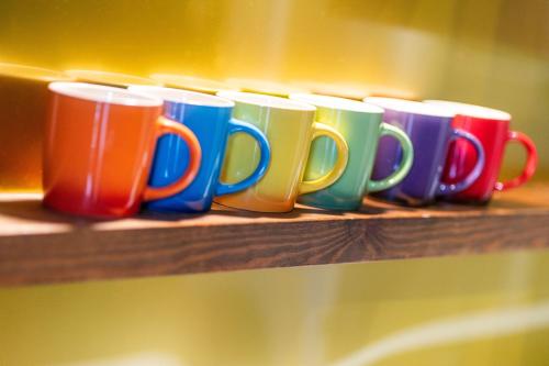 a row of colorful coffee mugs sitting on a wooden shelf at Central Apartments - Derelict in Blairgowrie