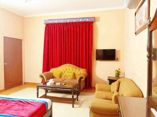 a living room with a couch and a red curtain at Calming Residence in Lahore