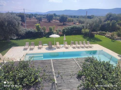 een zwembad met stoelen en een parasol bij Masseria Verbena suites in Macchia di Monte