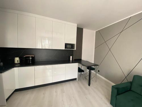 a kitchen with white cabinets and a table and a green chair at JD Apartment Świętokrzyska in Gniezno