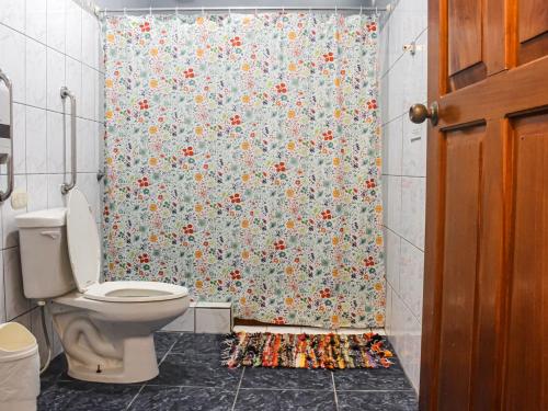 een badkamer met een toilet en een douchegordijn met bloemen bij La Posada - Hostel in Santa Teresa Beach
