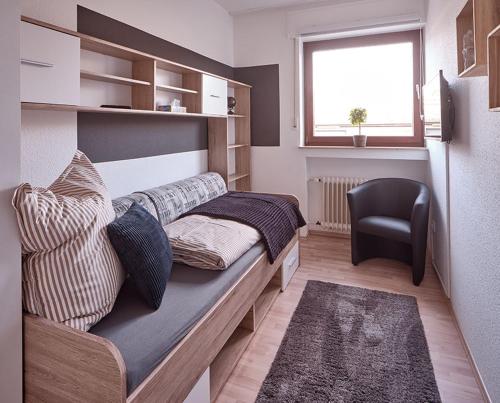 a bedroom with a bed with a chair and a window at KATARINAS HOUSE mit 2 FeWo stilvoll, gemütlich & zentral Boxspringbett, Parkplatz, Balkon oder Garten in Moers