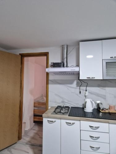 a kitchen with white cabinets and a stove top oven at Sobe kuća za odmor apartmani Auto Klarić in Nova Gradiška