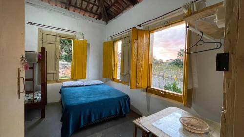 1 dormitorio con 1 cama, 2 ventanas y mesa en HOSTEL DA LÚ en Pirenópolis