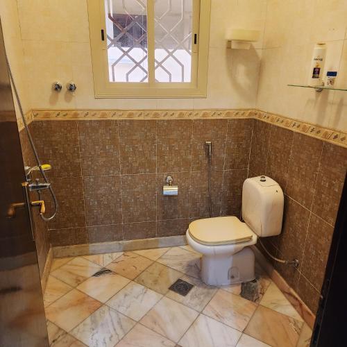 a bathroom with a toilet and a window at فيلا دورين وملحق in Miná