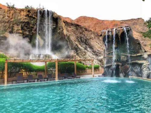 einem Wasserfall und einem Pool in einem Resort mit Stühlen und einem Wasserfall in der Unterkunft Laura's Stylish Villa in Madaba